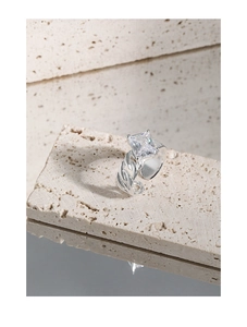 Macro detail of silver braided ring featuring a large square transparent gemstone setting