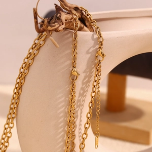 Detail of 18K gold-plated starfish necklace with clasp and chain tail on a white vase