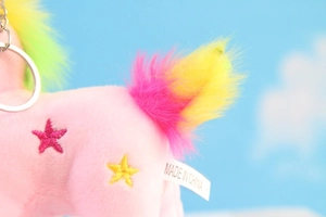 Dettaglio macro di un unicorno di peluche con coda arcobaleno e ricamo a stella