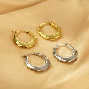 Boucles d'oreilles créoles texturées en or et argent sur fond de soie élégant