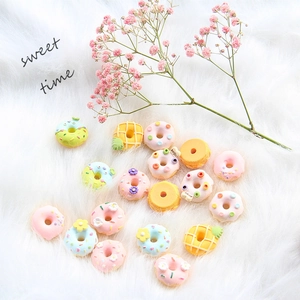 Flachbild von bunten Harz-Donut-Anhängern und Waffeln auf weißem Kunstfellhintergrund