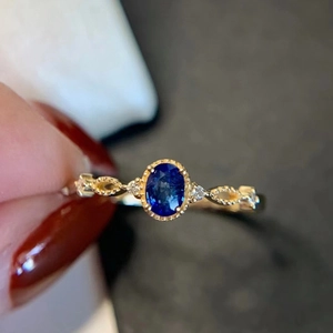 Detail of a gold lace ring featuring an oval blue sapphire and side accent stones