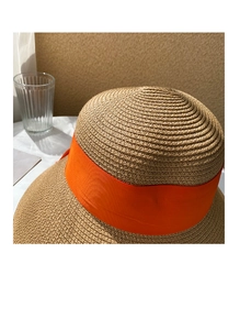 Close-up of woven straw texture and bright orange ribbon on khaki sun hat