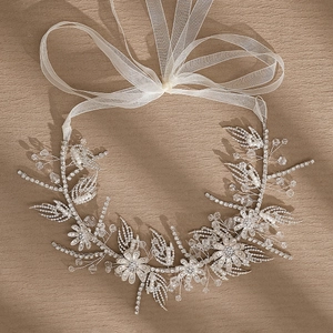 Elegant bridal floral headband with crystals, pearls and silver wire on beige surface