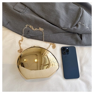 Macro view of golden shell-shaped evening bag with mirror finish and chain strap
