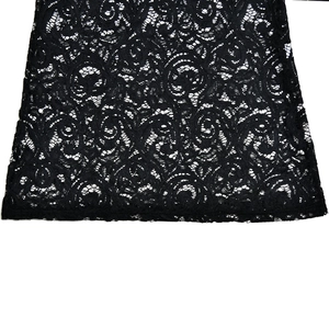 Close-up detail of black lace fabric showing intricate hollow floral embroidery patterns