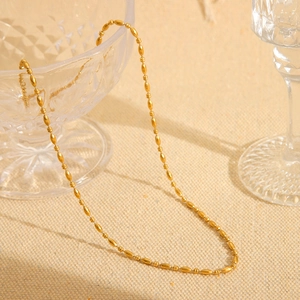 Close-up of 18K gold plated stainless steel beaded chain necklace on a beige fabric