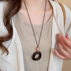 Vintage resin and wood oval pendant necklace on a minimalist linen blazer model