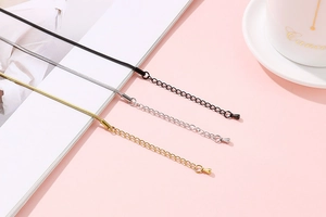 Close-up of gold, silver, and black snake bone chains with adjustable lobster clasps