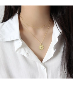 Vue détaillée du collier double rang doré avec pendentif médaillon sur un mannequin