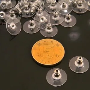 Silver bullet clutch earring backs with clear pad shown next to a coin for size reference
