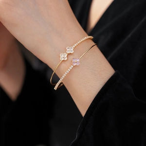 Detail of double-layer gold clover bracelet with pink and white zircon stones