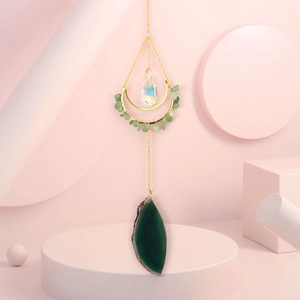 Detailed shot of green agate slice and crystal prism pendant on golden moon wind chime
