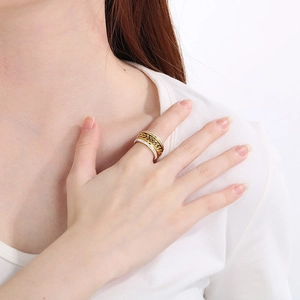 Détail d'une bague large dorée en acier inoxydable avec zircons portée par une femme