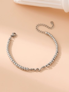 Detailed macro view of silver beaded stainless steel bracelet with wave pendant and lobster clasp