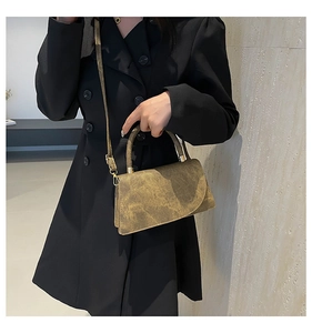 Detail shot of vintage brown textured leather handbag with metallic round handle and strap
