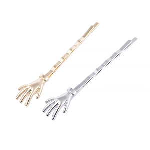 Detail showing two skull hand hair clips in gold and silver finish with metallic shine