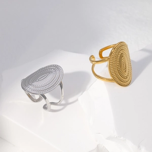 Detail of oval textured rings in gold and silver finish on a minimalist stone base