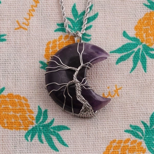 Macro shot of silver wire tree of life wrapped amethyst crescent moon pendant necklace
