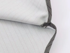 Macro detail of light gray twill fabric shirt showing stitching and pocket piping edges