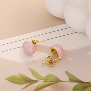 Close-up of teardrop enamel stud earrings with gold plating and pink marble pattern texture