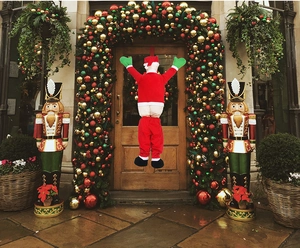 Funny Santa Claus hanging outdoor decoration climbing wall showing bottom for holiday porch