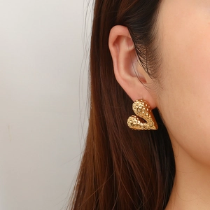 Golden 18K stainless steel heart earrings with unique liquid texture on female model