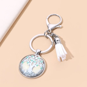 Tree of Life keychain with silver pendant and white tassel on minimalist background