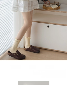 Detail of cream yellow cotton socks featuring elegant ruffle cuffs in a cozy home setting