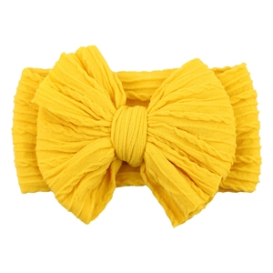 Detail of yellow nylon headband featuring a large knitted jacquard bow for babies