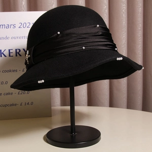 Elegant black wool cloche hat with ruffle edge, satin ribbon and pearl cross accents