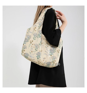 Close-up of floral canvas tote bag with blue hydrangea patterns on a model's shoulder