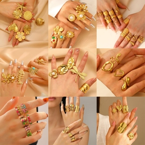 Golden stainless steel rings with floral heart and starfish designs on silk background