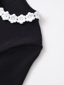 Detail of white crochet flower lace on the crew neckline of a black knit short sleeve T-shirt
