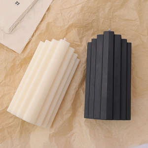 Minimalist beige and black striped pillar candles on textured crumpled paper background