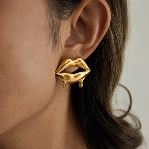 Macro detail of gold liquid cherry earrings on model showing glossy metallic drip design