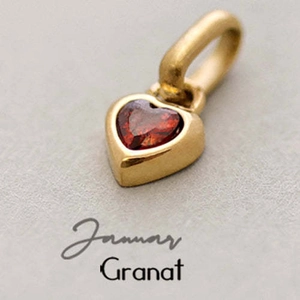 Macro shot of gold heart pendant with red garnet gemstone for January birthday