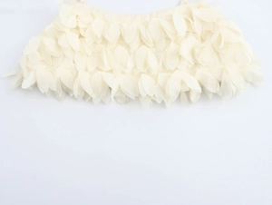 Detailed close-up of 3D layered fabric flower petals on a cream-colored crop top