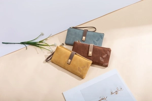 Close-up of vintage frosted leaf buckle wallets in misty blue, brown, and yellow colors