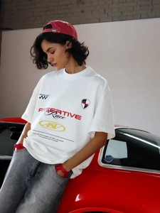 Κοντινό πλάνο λευκού racing t-shirt με γράμματα και φόντο ένα vintage αυτοκίνητο