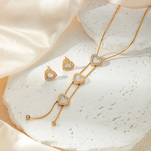 Detailed macro view of gold heart necklace and earrings set with pearl and zircon inlay