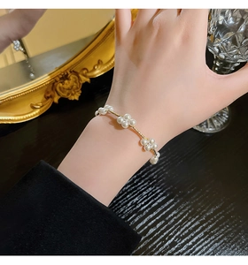 Detail of elegant pearl bracelet featuring delicate zircon flower patterns on a wrist
