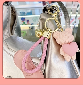 Macro detail of a pink textured resin bear keychain with a heart on a silver bag