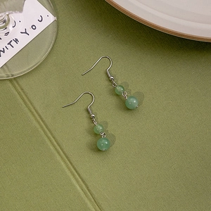 Detailed view of green jade bead earrings with silver hooks and elegant drop tassels