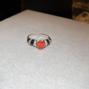 Close-up of red oval zircon ring with black enamel and white crystal detailing