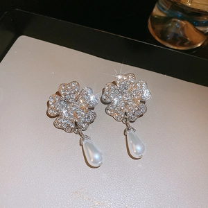 Detail of luxury clover earrings with sparkling crystals and white teardrop pearls
