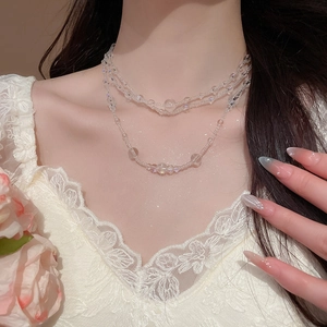 Close-up of a multi-layer glass bead necklace worn with a cream lace dress and rose
