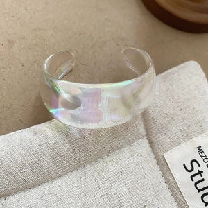 Macro detail of iridescent acrylic cuff bracelet showing rainbow colors on smooth surface