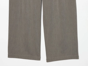Gros plan détaillé du bas d'un pantalon gris foncé montrant la texture du tissu tissé