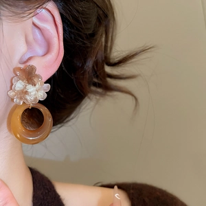 Close-up of vintage resin flower pendant earring worn by a model in soft lighting